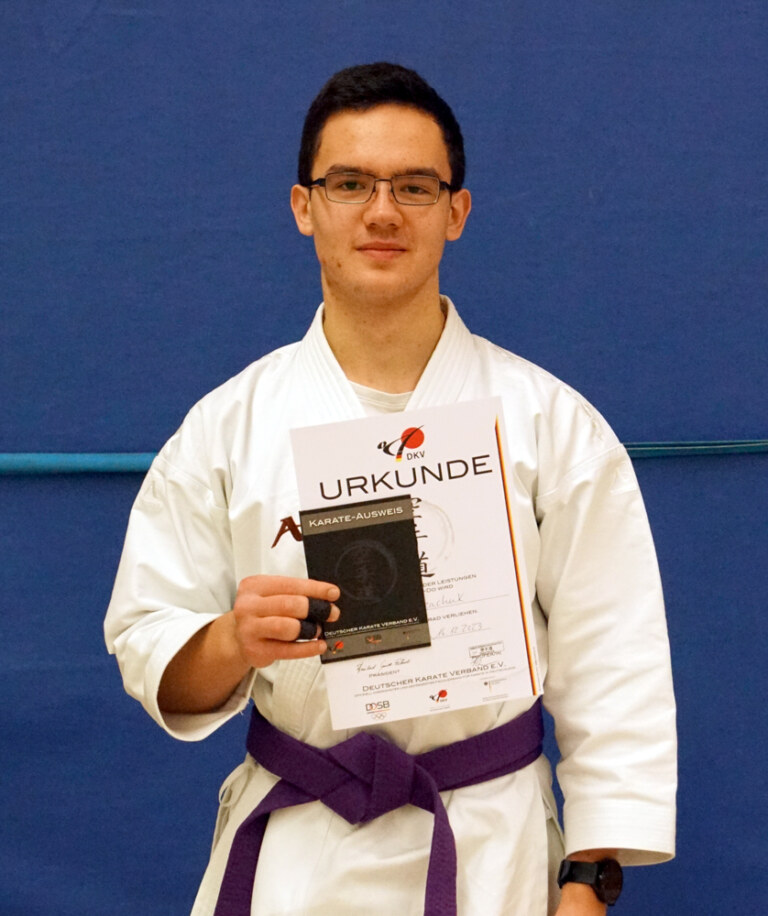 Karateka mit Urkunde und lila Gürtel.