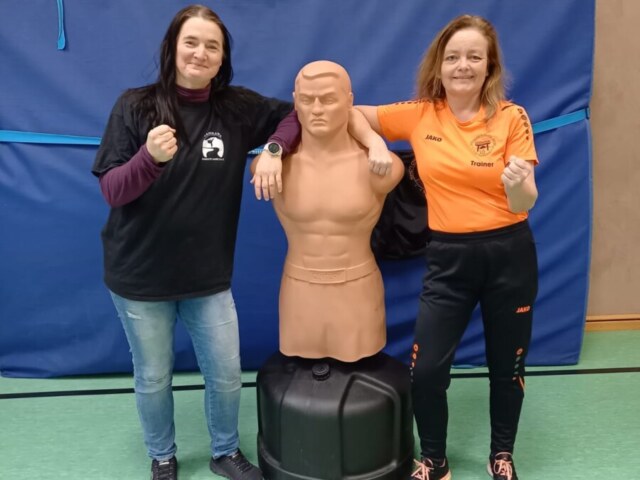 Zwei Personen posieren mit Trainingsdummy.
