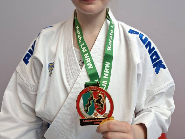 Karateka im weißen Gi zeigt NRW-Landesmeisterschaftsmedaille