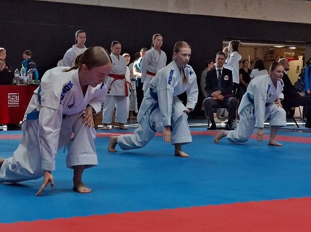 Karateka starten auf Wettkampfmatte in Sporthalle
