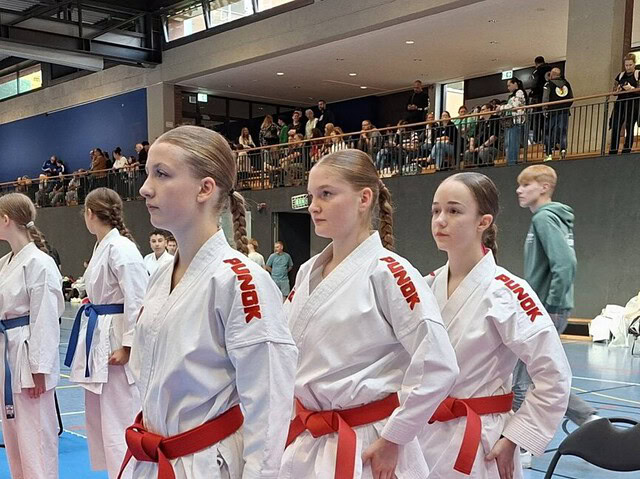 Junge Taekwondo-Sportlerinnen mit roten Gürteln in einer Sporthalle