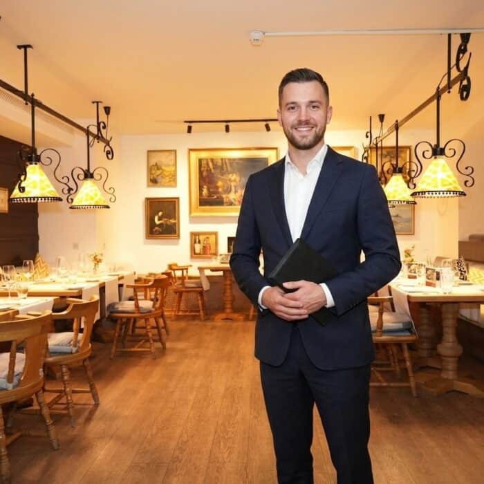 Mitarbeiter im Anzug steht mit einer Mappe im Restaurant Brunnenhof des Central-Hotel Kaiserhof
