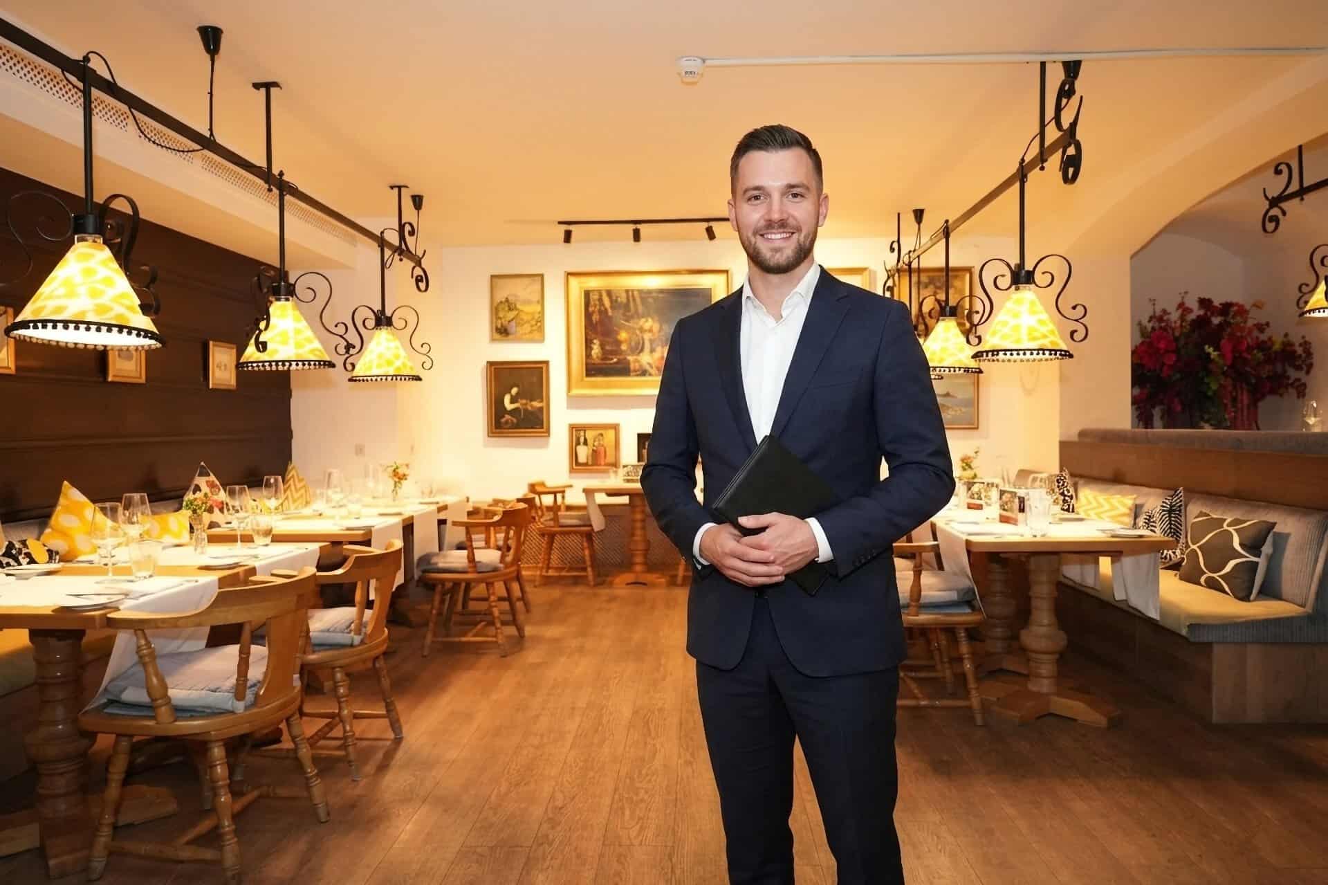 Mitarbeiter im Anzug steht mit einer Mappe im Restaurant Brunnenhof des Central-Hotel Kaiserhof