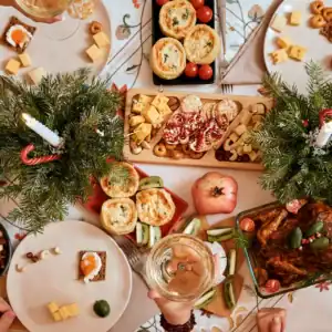 Weihnachtlich gedeckter Brunch-Tisch mit Braten, Vorspeisen-Häppchen und Nussschalen zwischen Deko aus Tannenzweigen