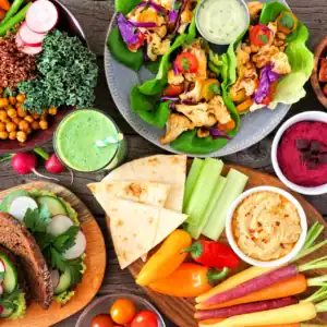 Große Auswahl an veganen und vegetarischen Speisen auf rustikalem Holztisch.