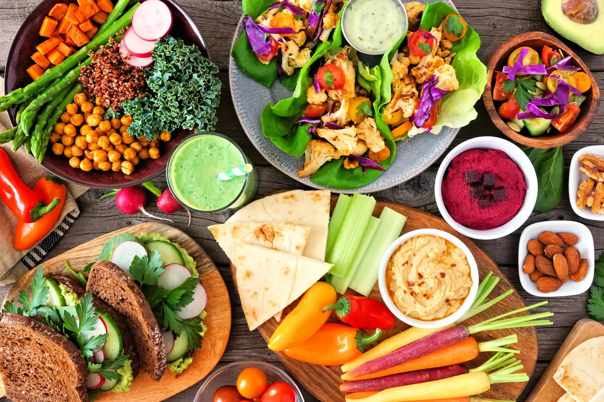 Große Auswahl an veganen und vegetarischen Speisen auf rustikalem Holztisch.