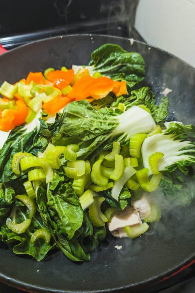 adding celery and peppers to wok