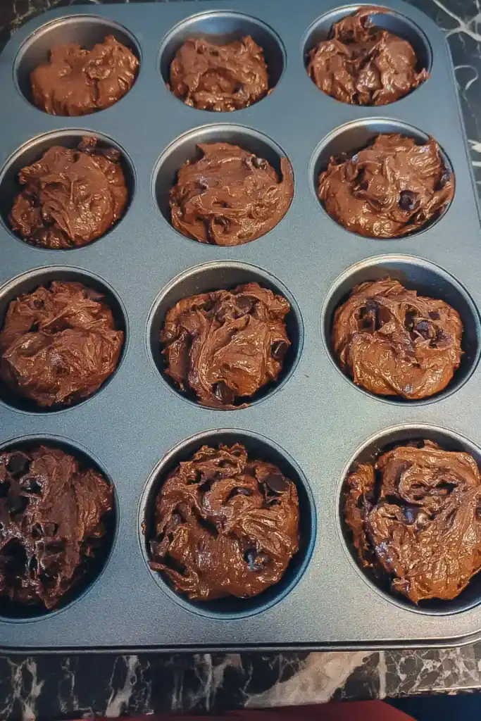 filling the muffin tin with the chocolate orange batter