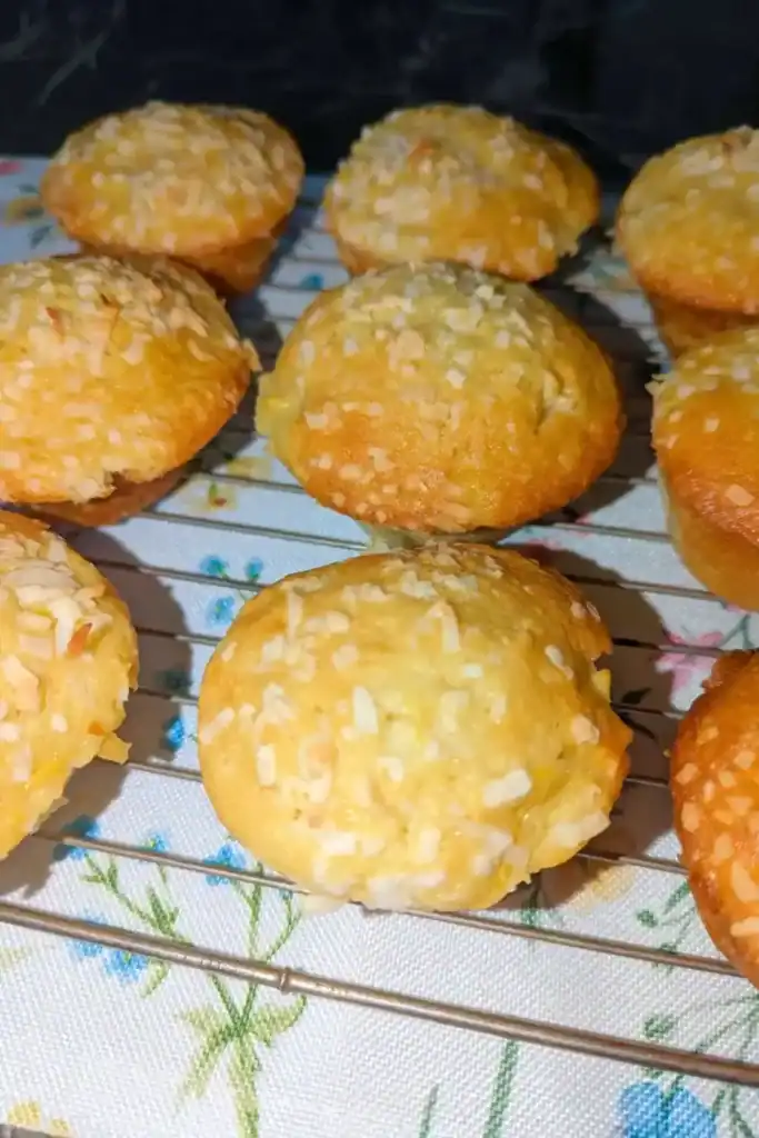 baked peach coconut muffins cooling on a wire rack with floral placemat underneath