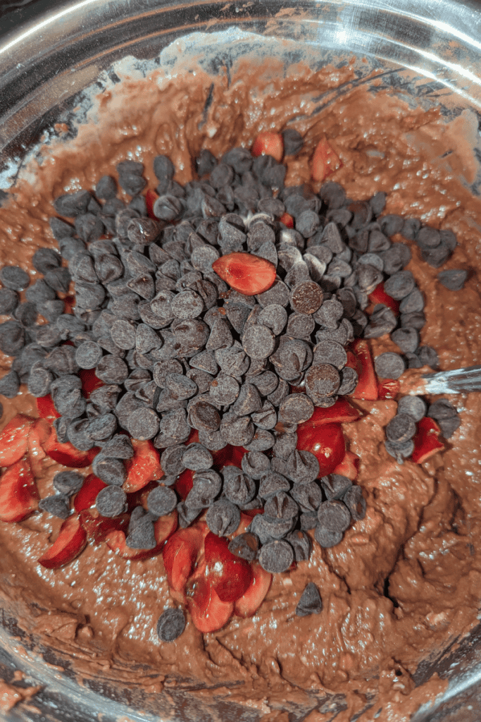 adding cherries and dark chocolate chips to chocolate cherry muffin batter