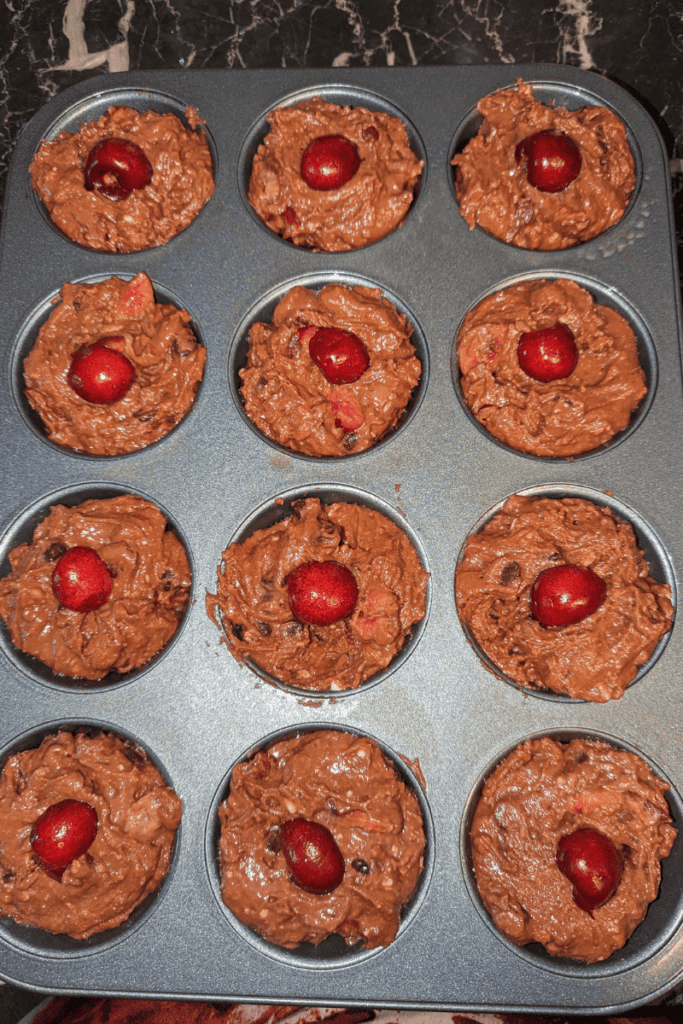filling chocolate cherry muffin tins and adding cherry halves on top
