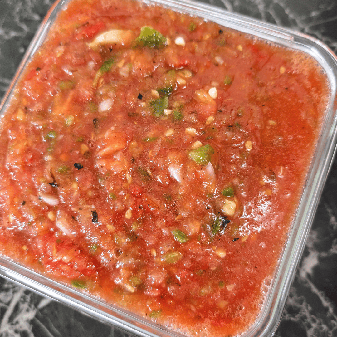 Fresh roasted tomato salsa with cilantro and garlic in a glass container.