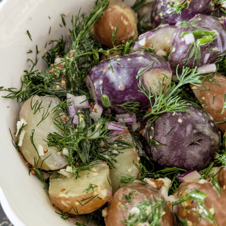 Baby potatoes with dill, herbs, and onion in a bowl for Baby Potato Salad.