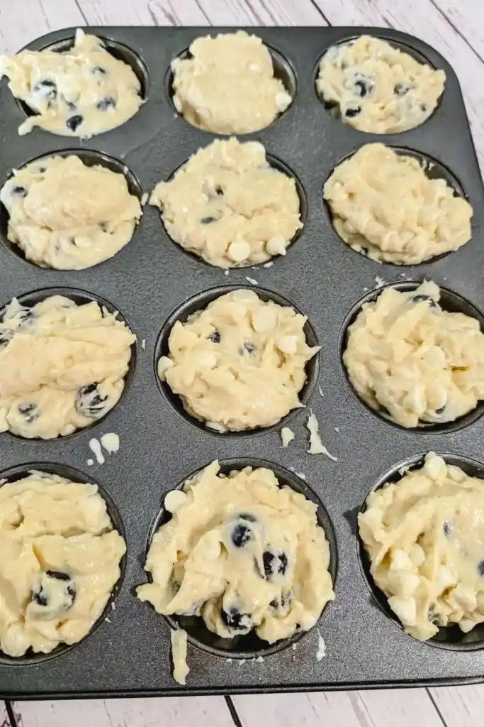 filling the muffin tins with the blueberry lemon cheesecake muffin batter