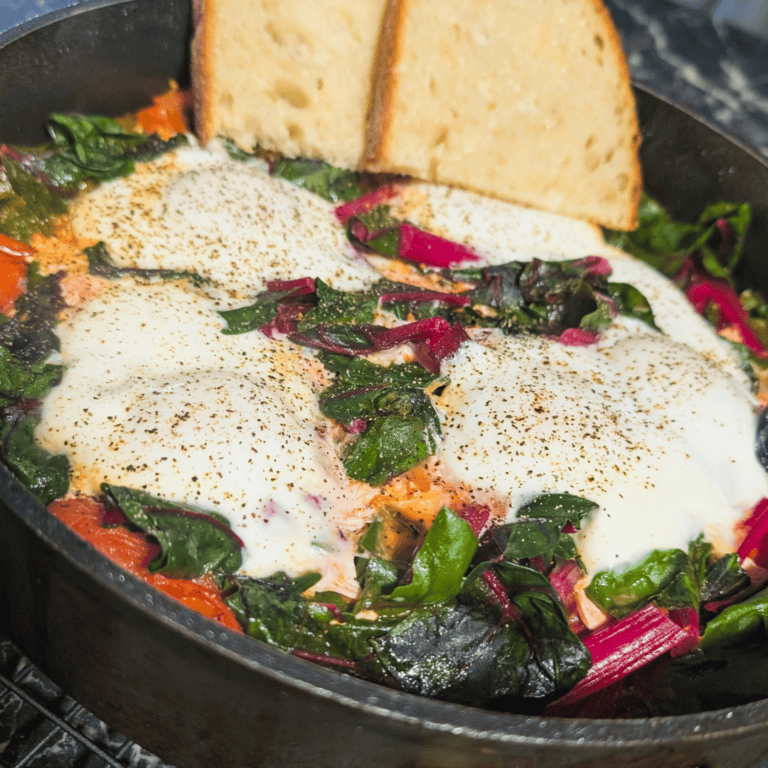 Eggs in Purgatory with greens and toasted bread, perfect for a flavorful breakfast.