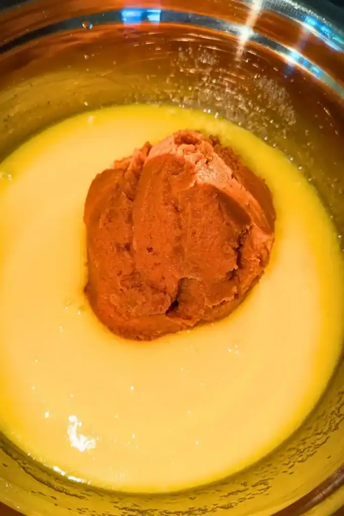 adding pumpkin puree to wet ingredients in mixing bowl