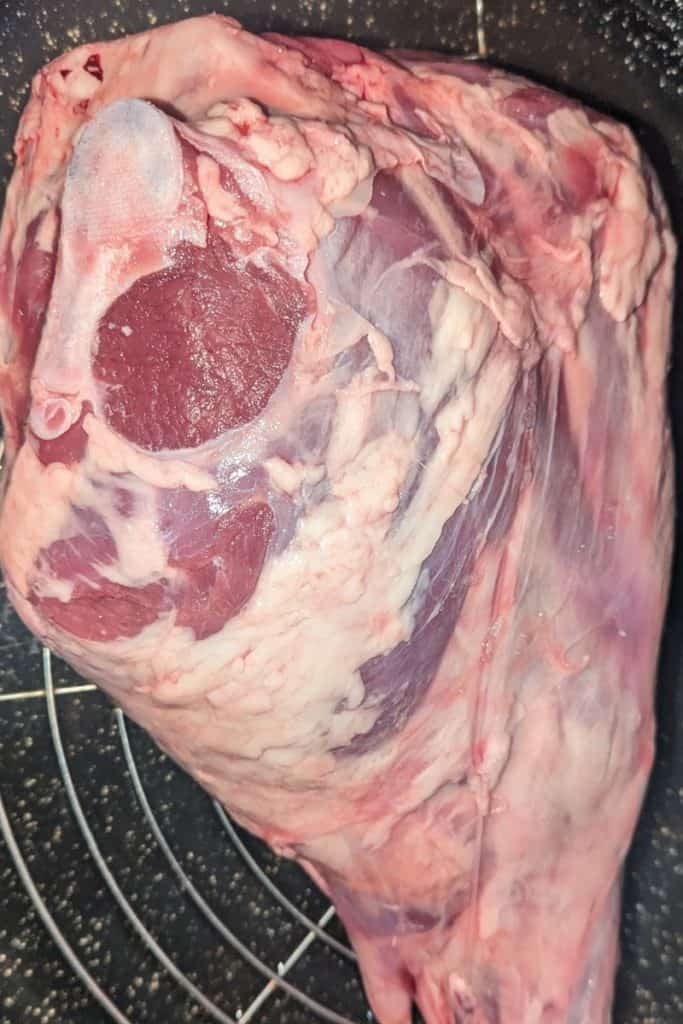 adding leg of lamb to roasting pan