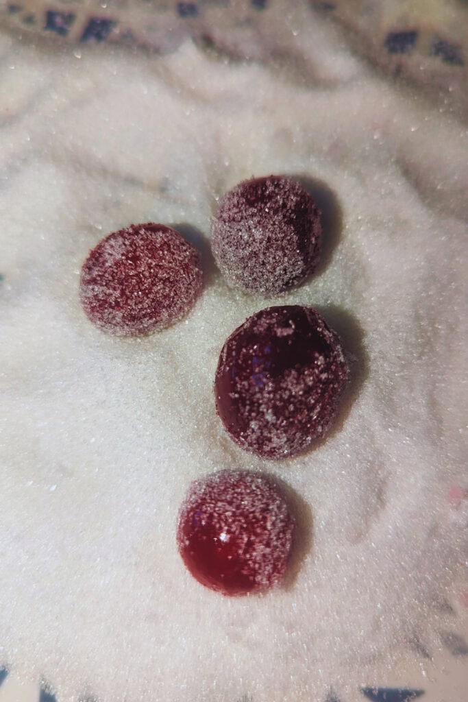 rolling sugared cranberries in white sugar