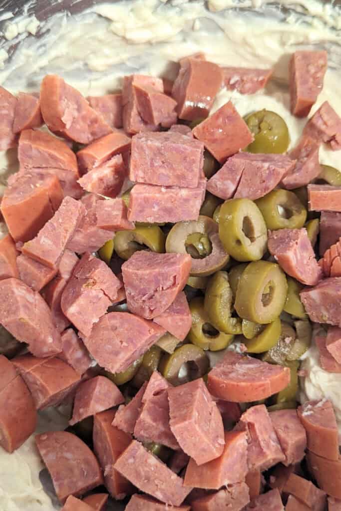 adding chopped pepperoni to dip mixture