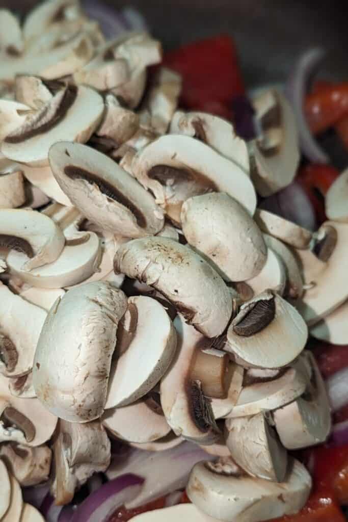 adding sliced mushrooms to cooked onion and peppers