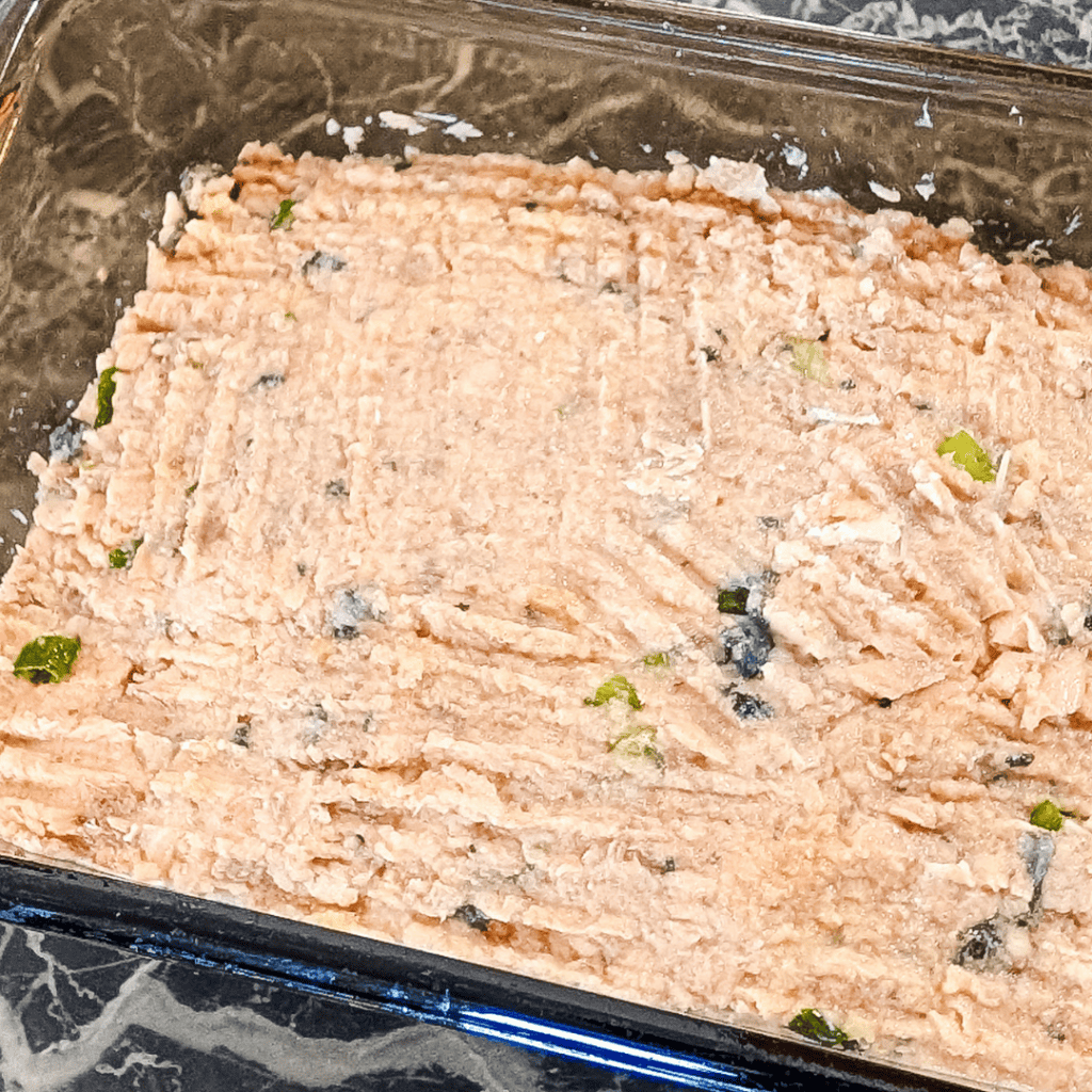 Fresh homemade tuna salad with herbs and black pepper in a glass dish.