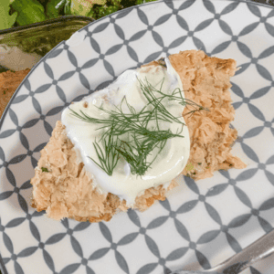 salmon loaf with creamy dressing and herbs on decorative plate.