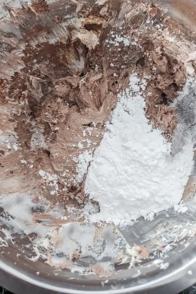 adding cocoa powder and icing sugar to cream cheese