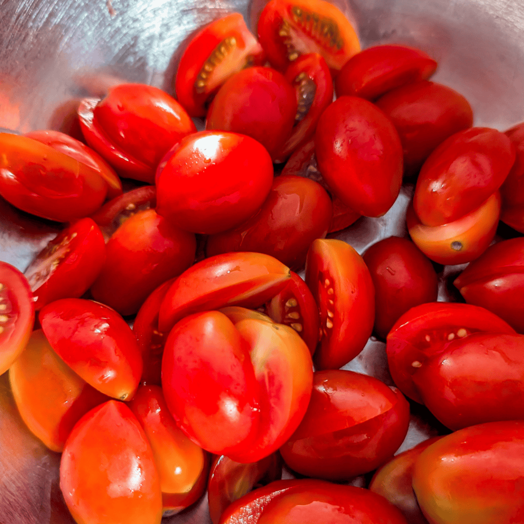 Fresh cherry tomatoes, halved, showcasing their vibrant red color.