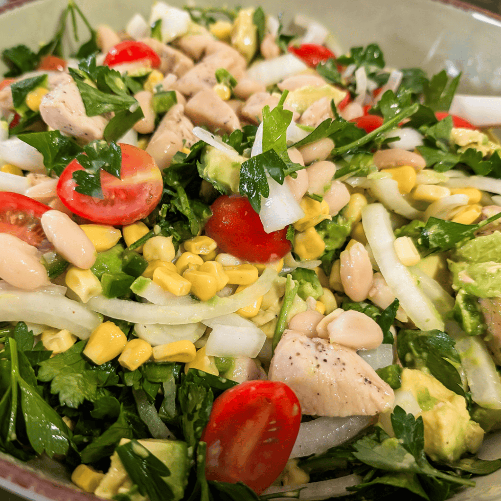 Healthy chicken wrap salad with cherry tomatoes, corn, onions, and herbs for a delicious meal.