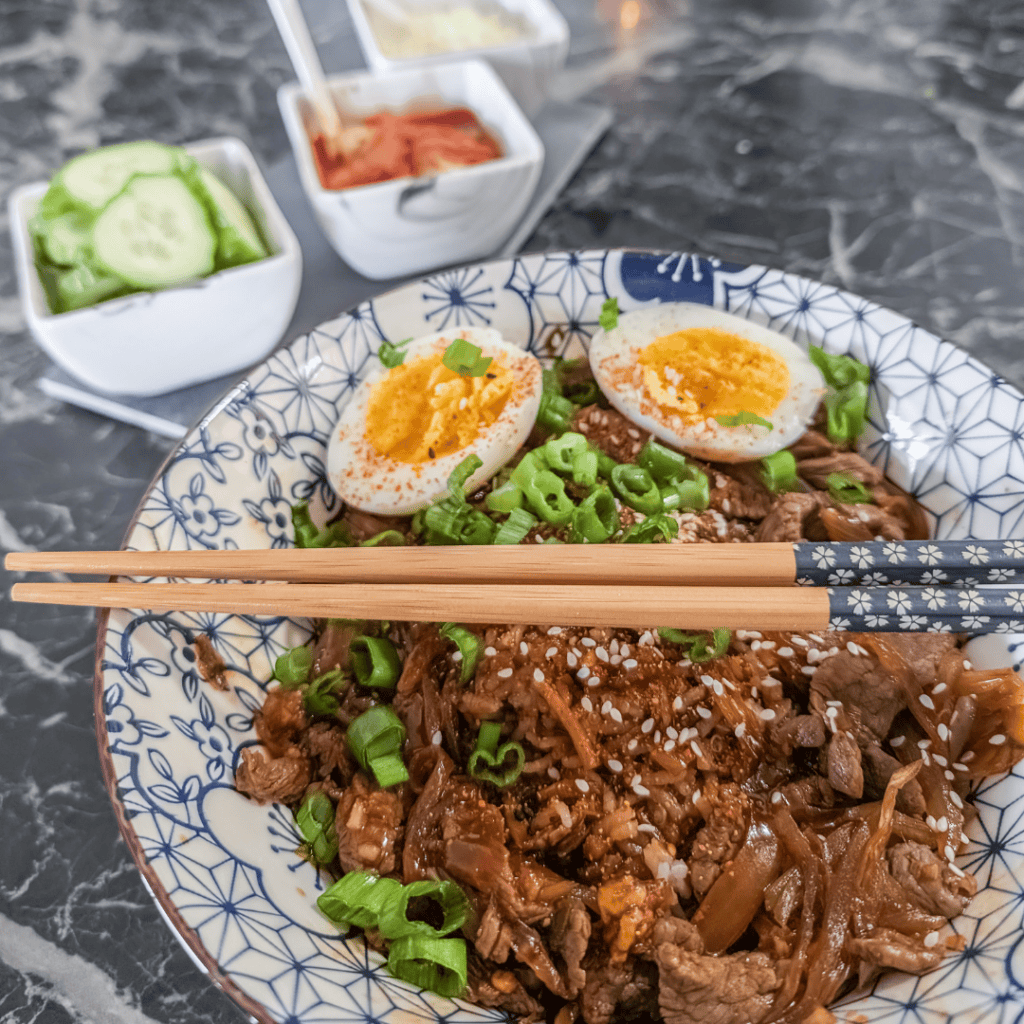 Delicious Japanese Gyudon beef rice bowl with boiled eggs and fresh vegetables.