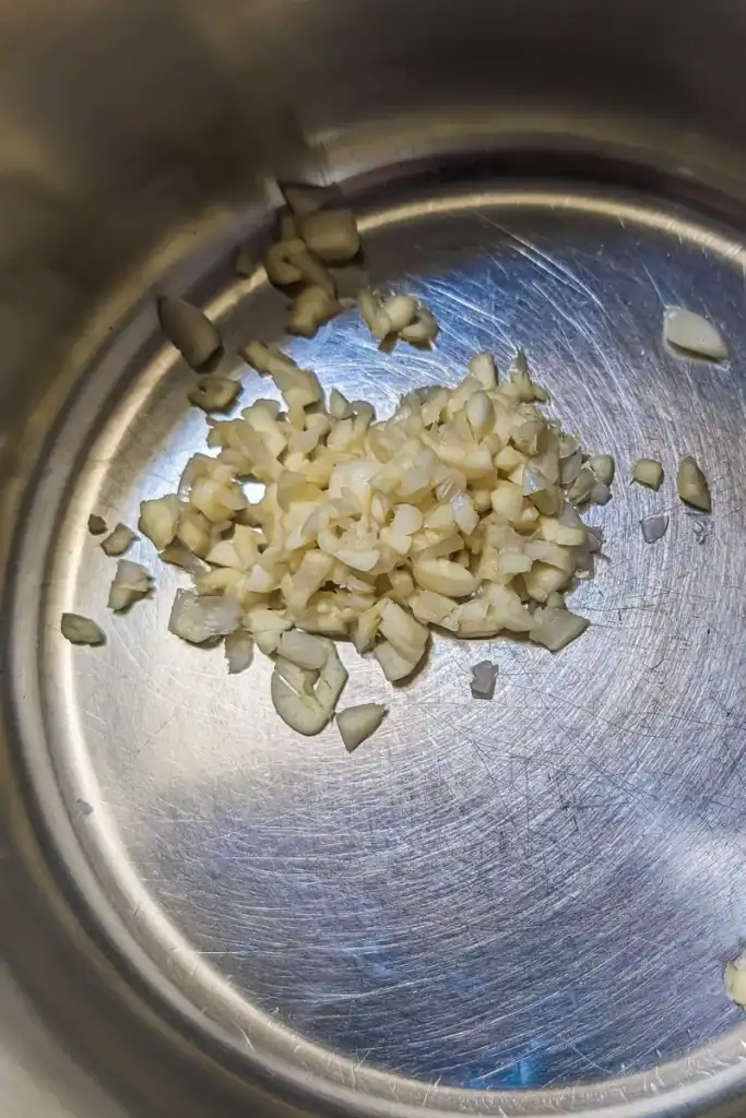 adding minced garlic to saucepan