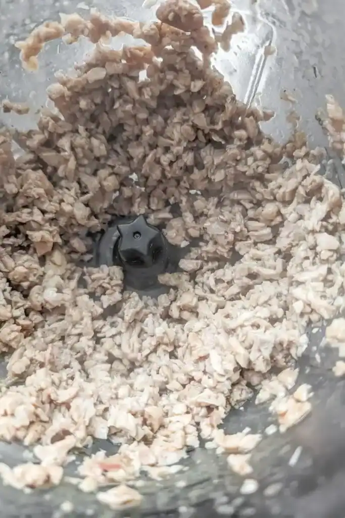 cutting the cooked chicken thigh meat up in the food processor
