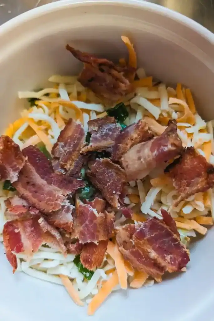 crips bacon broken on shredded cheese blend with green onion in bowl