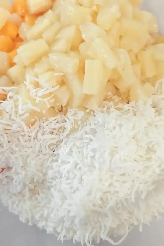 adding semi sweetened coconut shreds to fruits in salad
