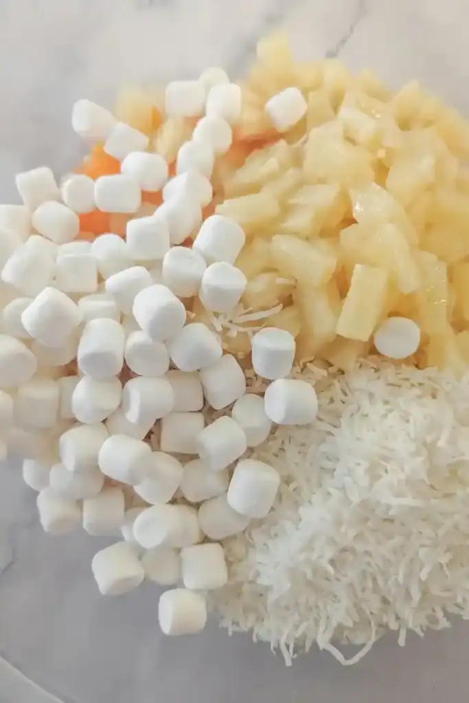 adding miniature white marshmallows to ambrosia salad