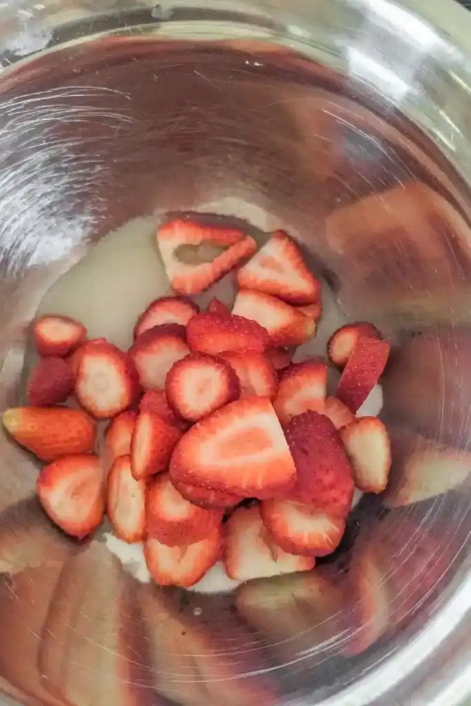 adding sliced strawberries and egg whites to sugar