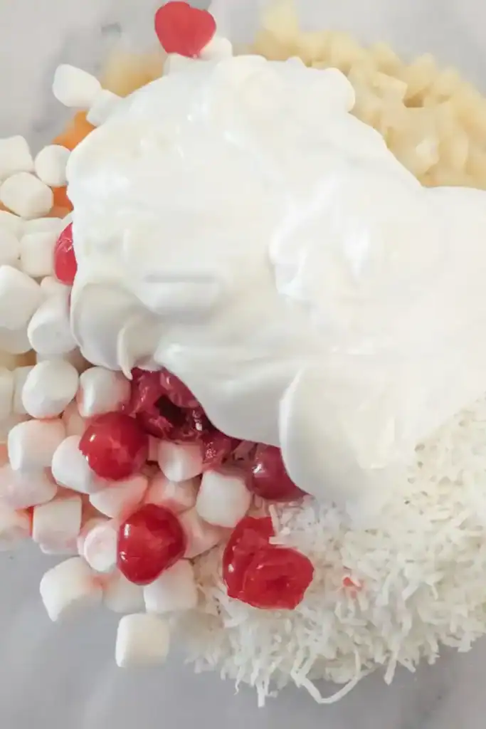 adding sweet cream salad dressing to fruit salad
