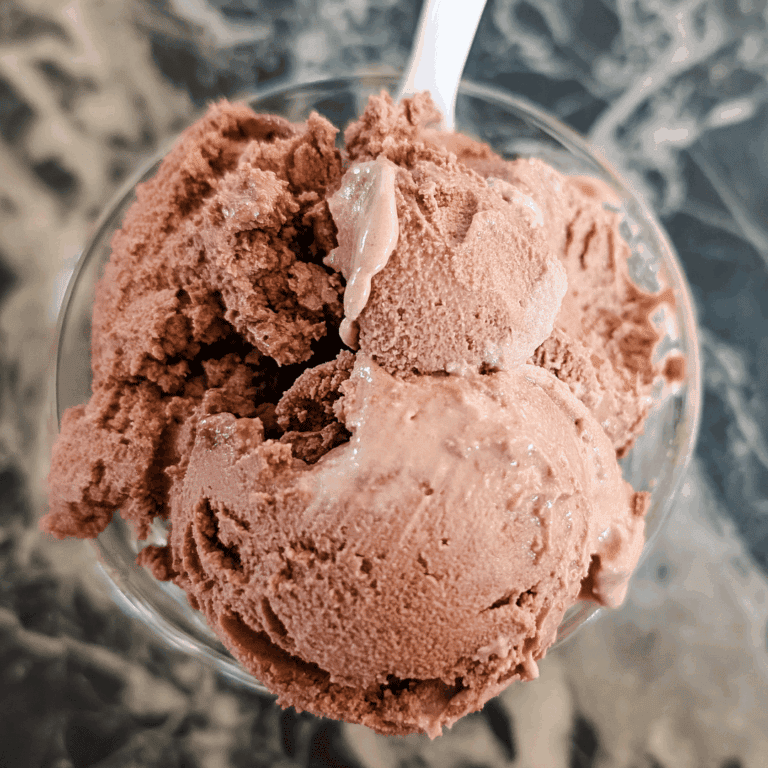Creamy chocolate ice cream scoop in a glass bowl, perfect for dessert.