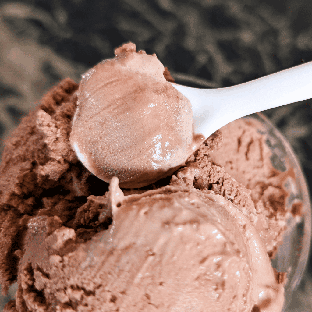 Creamy chocolate ice cream scoop in a bowl, close-up shot.