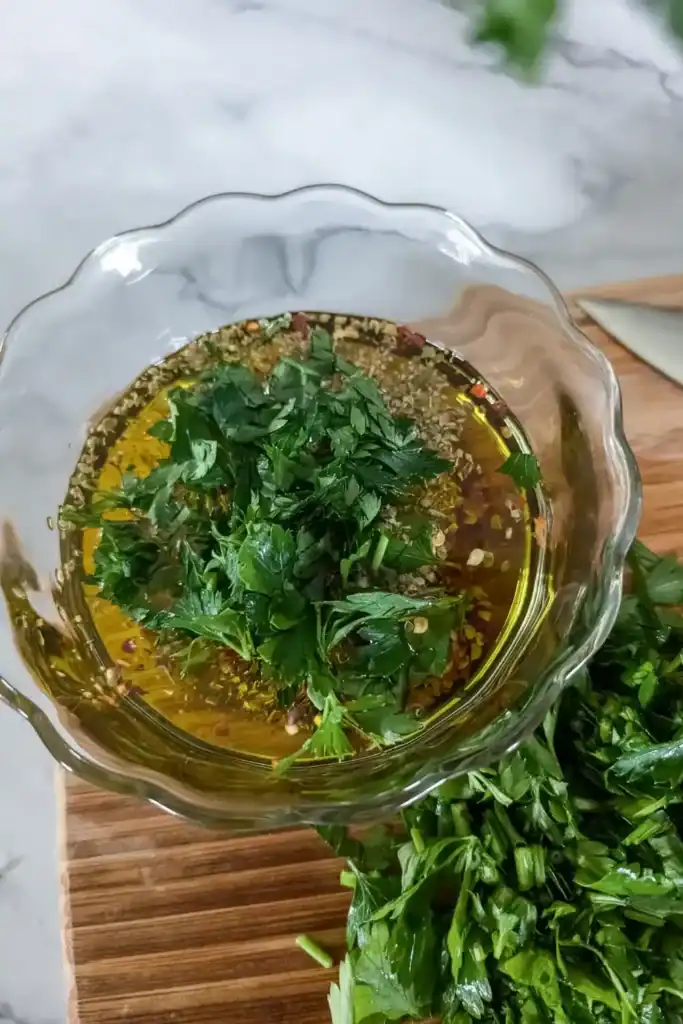 adding parsley to chimichurri sauce