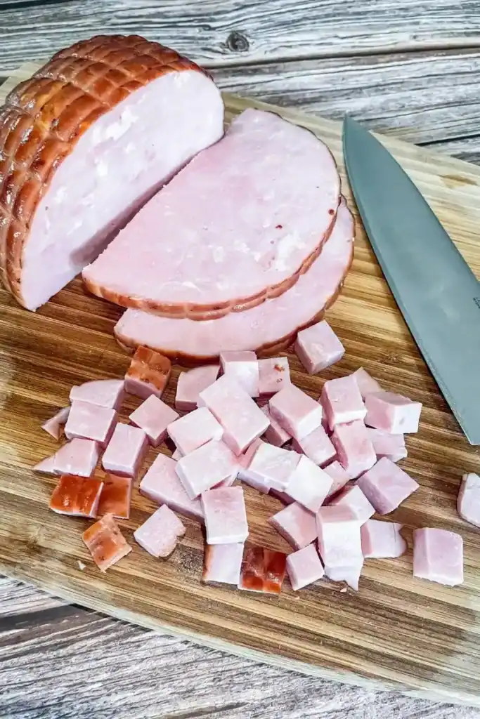 diced cooked ham on cutting board with knife and ham