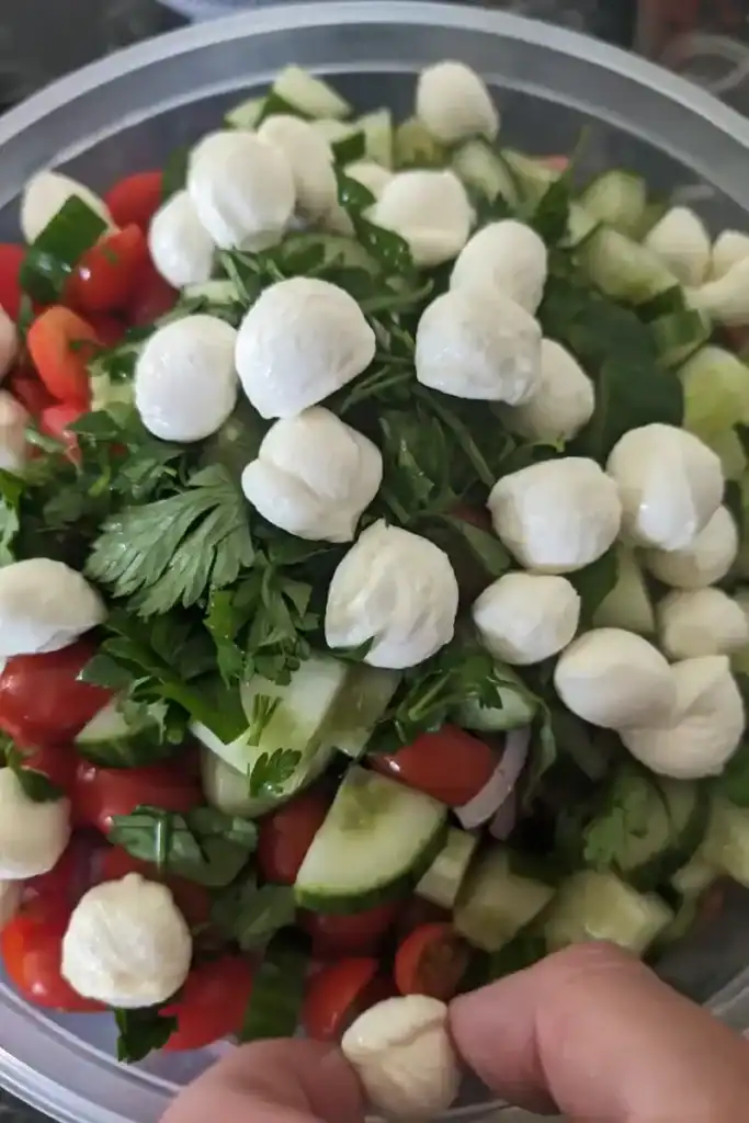 adding fresh mozzarella cheese balls to the salad
