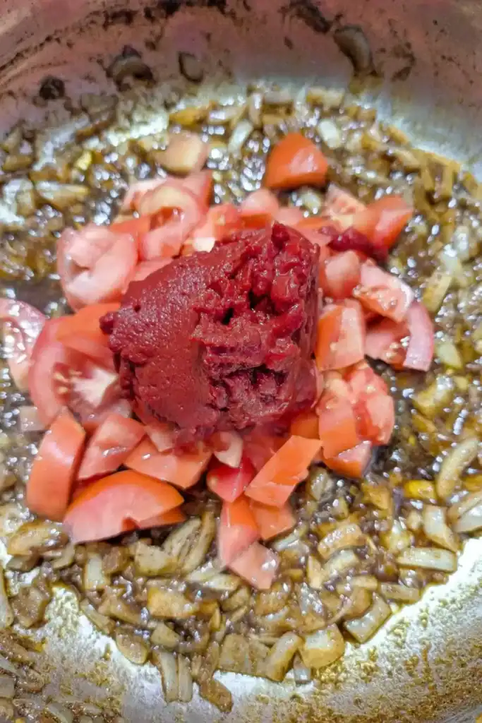 adding tomato paste to sauce