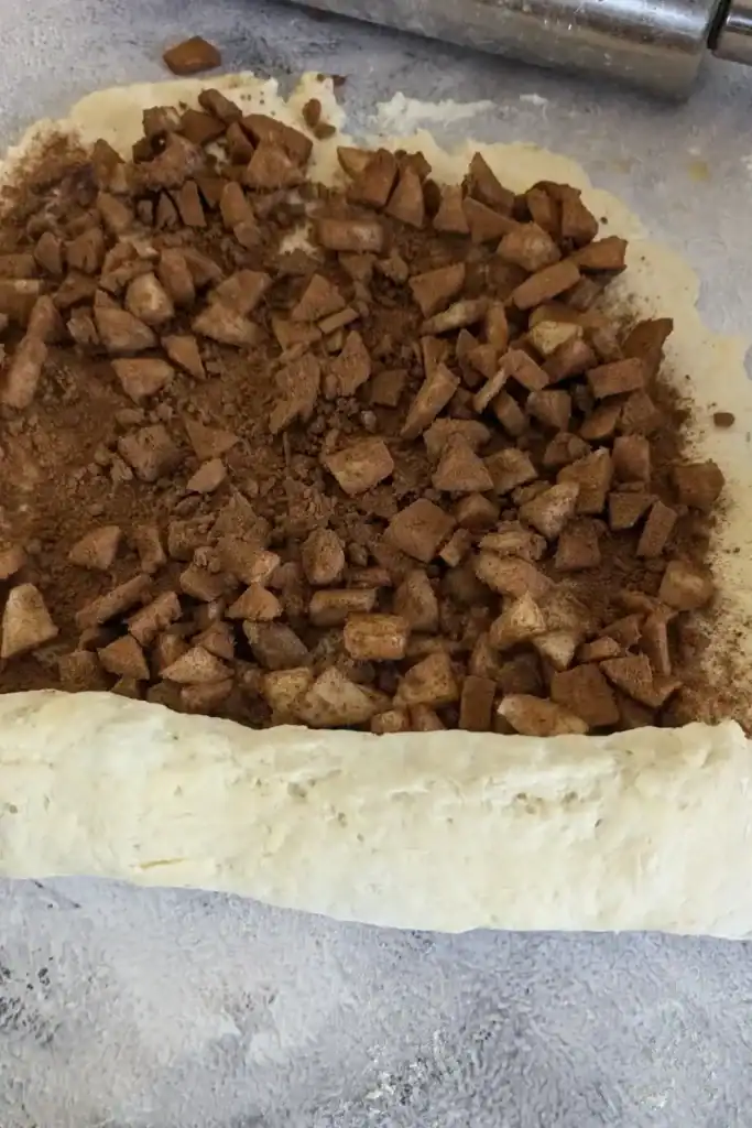 Rolling the apple cinnamon biscuit dough from the narrow end of the rectangle