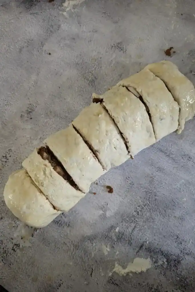 evenly slicing the apple cinnamon biscuit roll log into seven equal pieces for baking