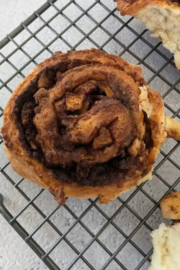 close up of one of the baked apple cinnamon rolls cooling on wire rack