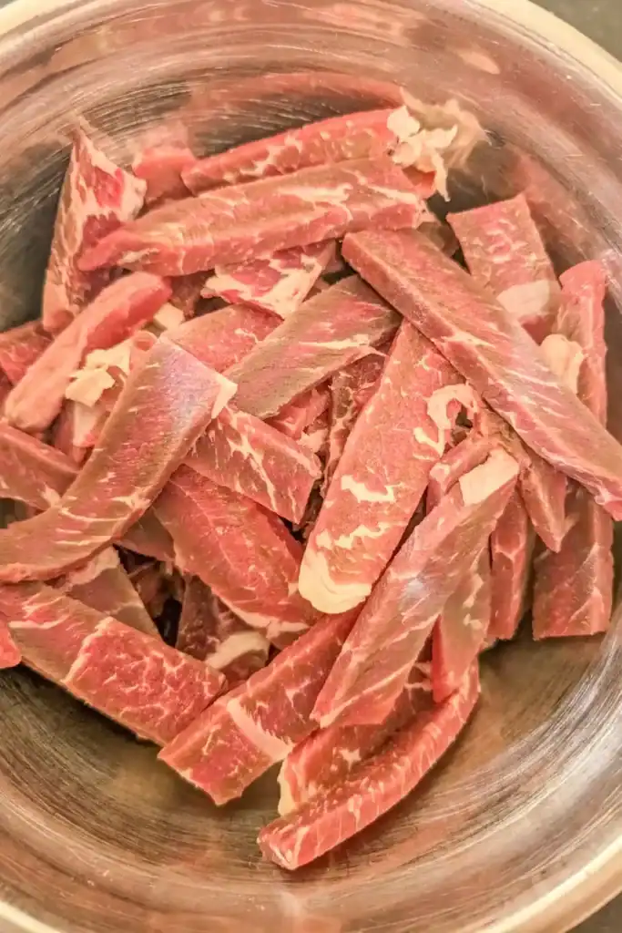 raw beef strips in stainless steel bowl