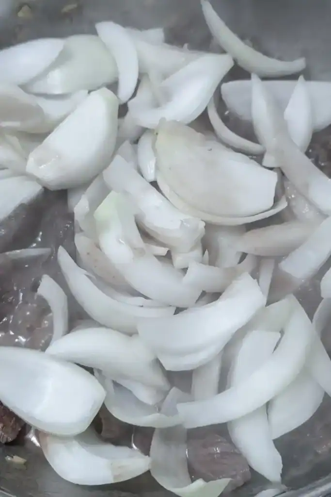 adding the sliced sweet onion to the beef stir fry dish