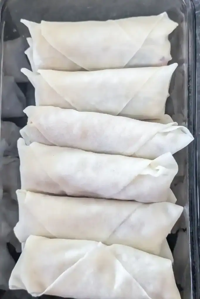 finished uncooked shrimp spring rolls stacked in dish