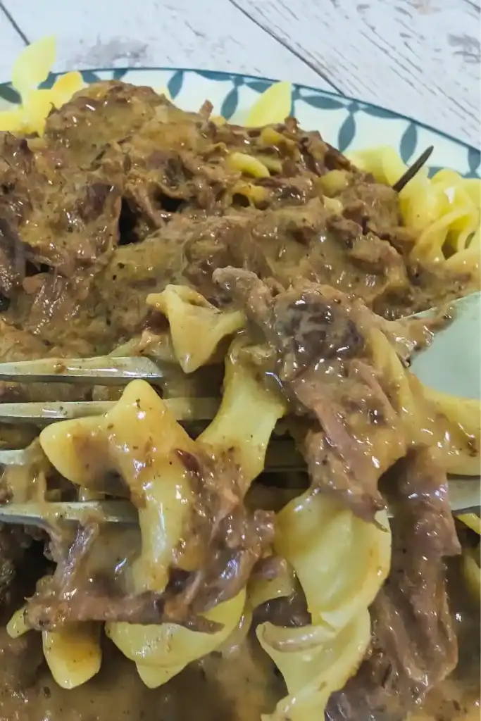 a close up of a forkful of the rich beef and noodle